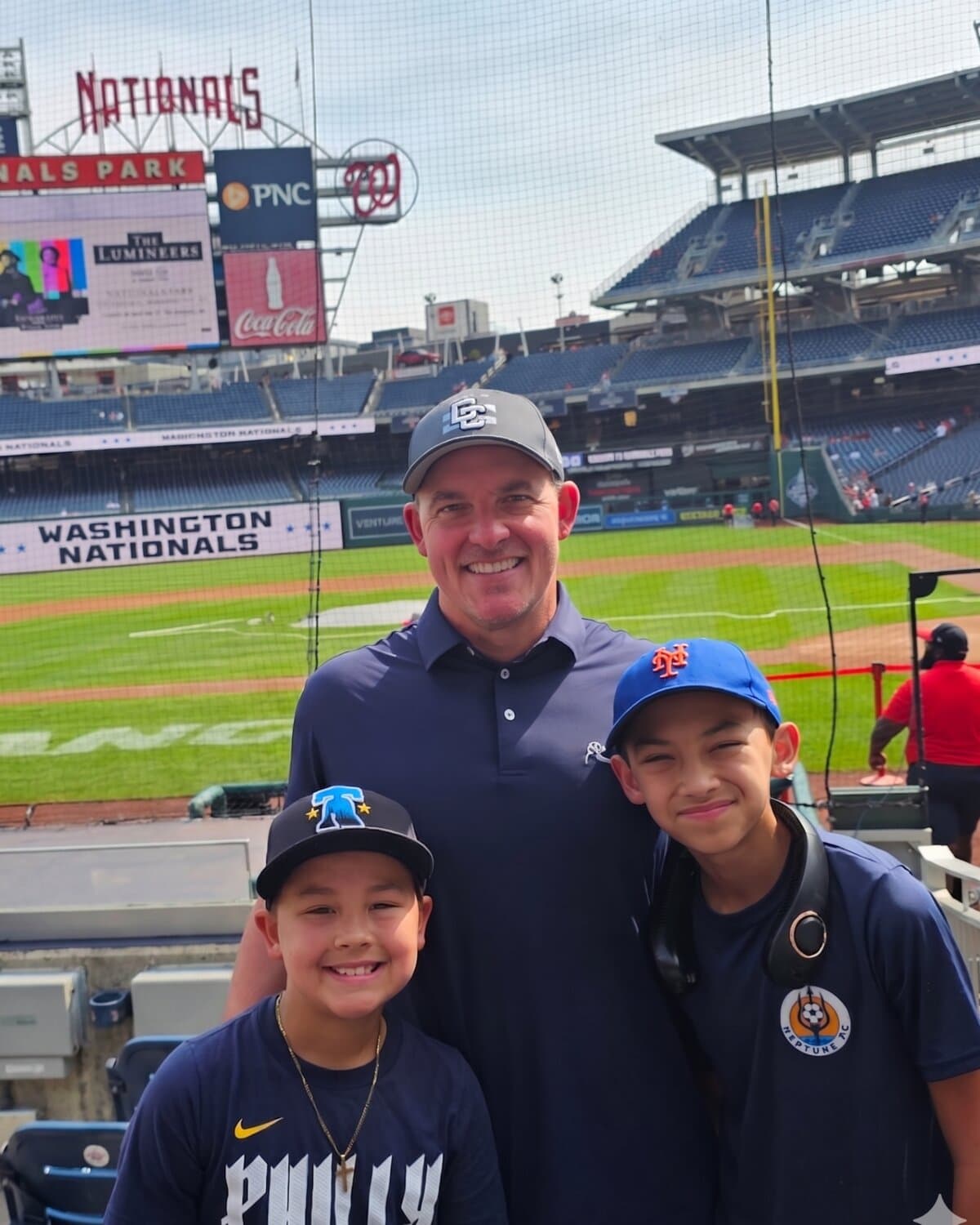 Dr. Russ Beach with his two sons at Nationals Park, Washington D.C., his younger son Greyson standing front-center in a Phillies shirt