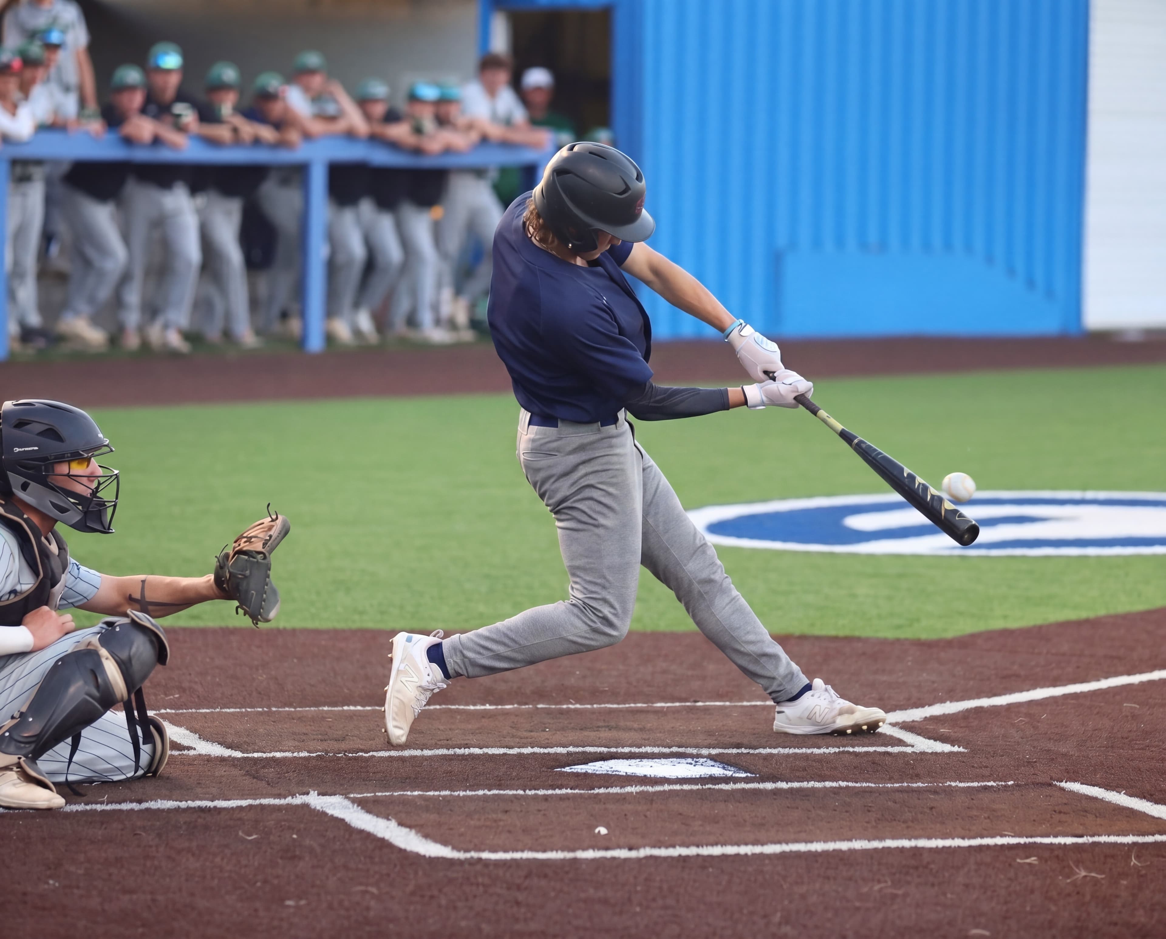 Young baseball player making contact with a pitch, eyes locked on the ball at the moment of impact